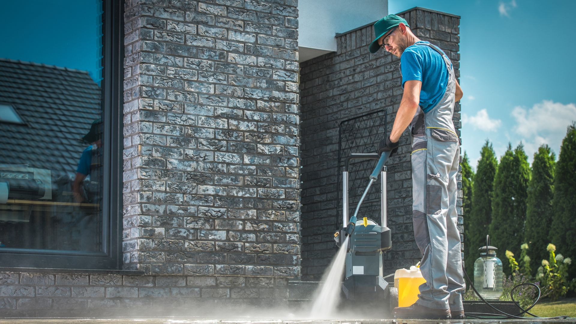 professional in work uniform pressure washing concrete