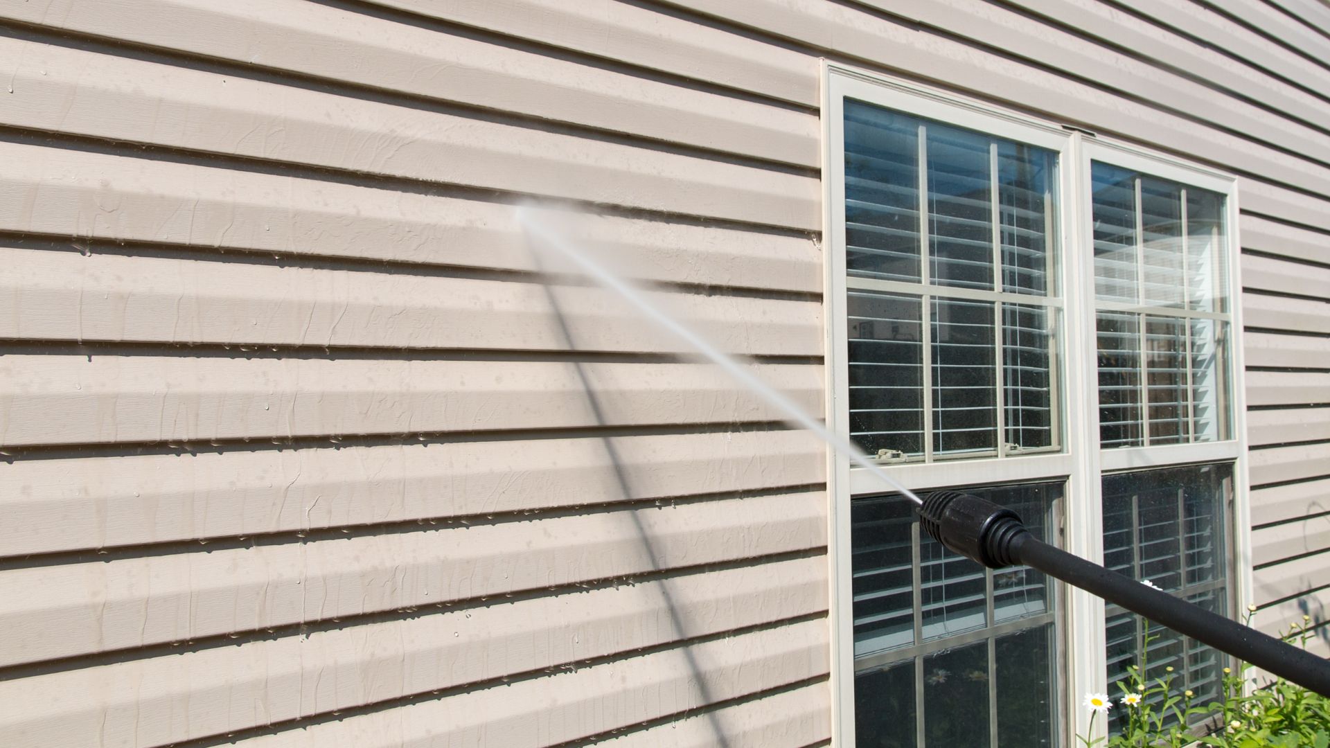 professional pressure washing siding of white home