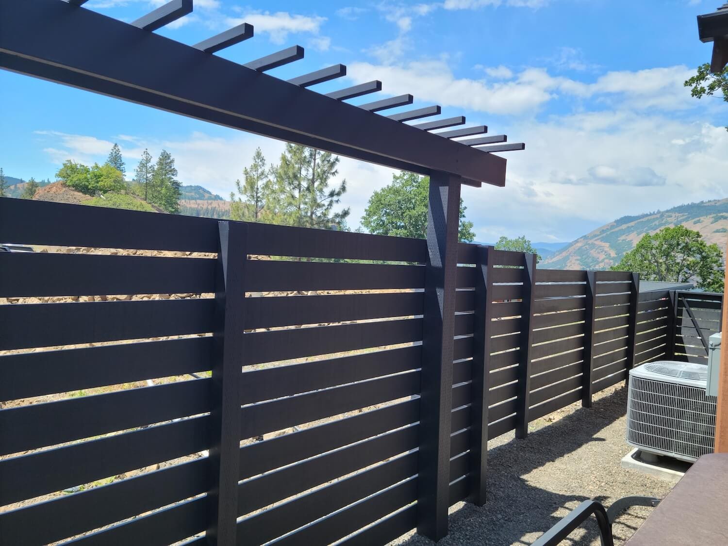 Painter staining a wood deck railing at a Parkdale, OR home