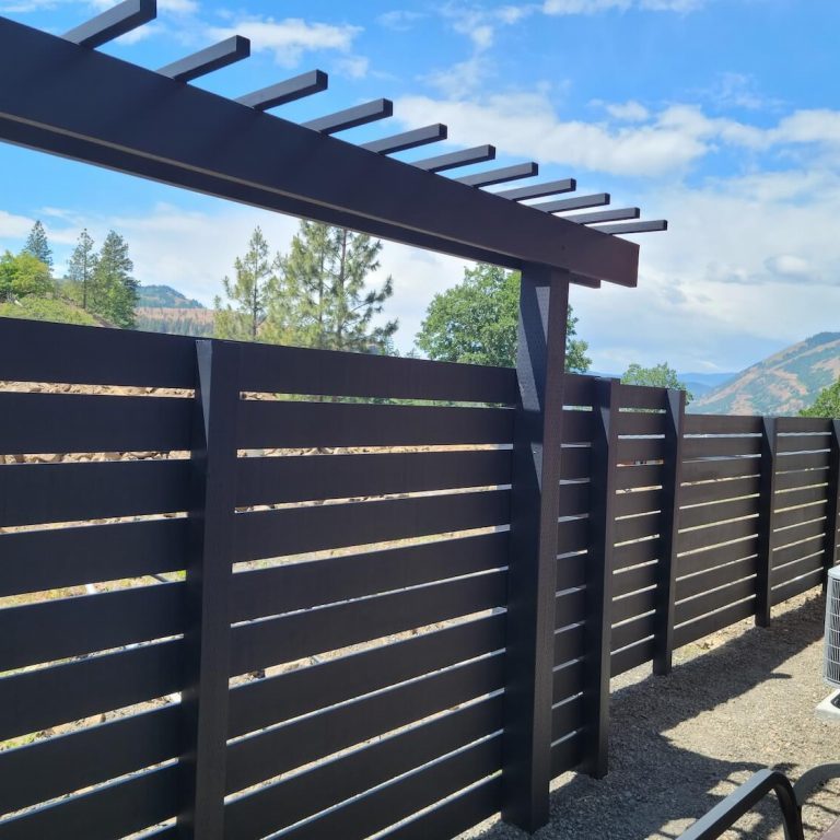 Painter staining a wood deck railing at a Parkdale, OR home